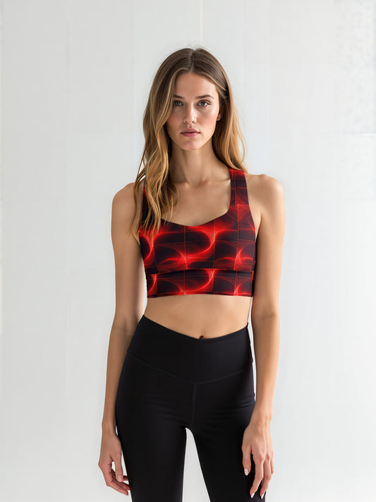 Woman wearing a Blaze Ignite longline sports bra with a bold red and black abstract pattern, paired with high-waisted black leggings, standing against a plain light background.