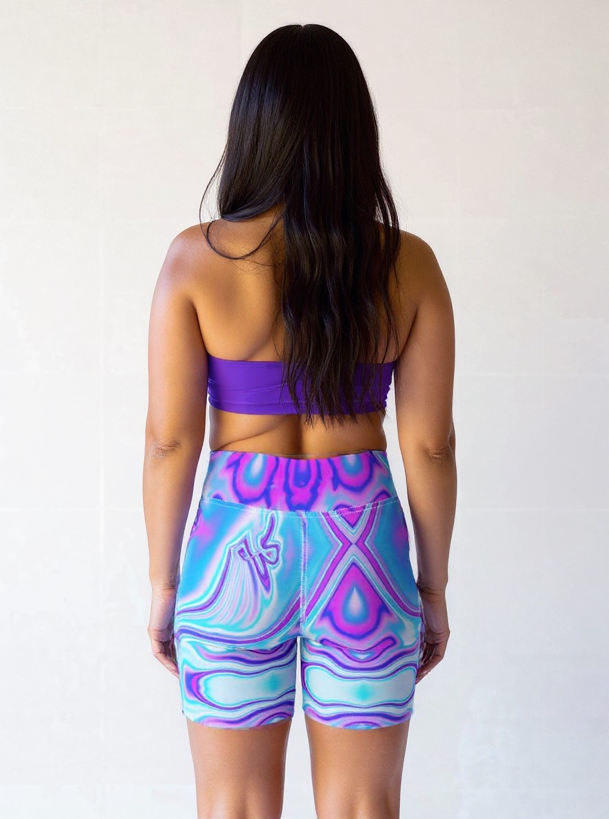 Plus-size woman shown from the back wearing Dreamwave Yoga Shorts with a vibrant blue, purple, and pink swirl pattern, paired with a purple sports bra.