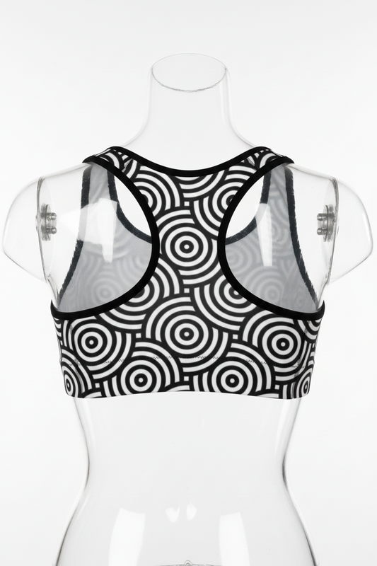 A black and white cropped tank top with a bold concentric circle target pattern and contrasting white shoulder panels, shown against a plain white background.