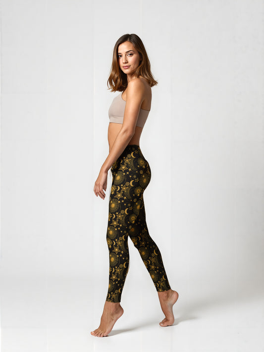 Side view of a woman wearing Midnight Halo yoga leggings featuring a celestial gold star, moon, and sun pattern on a black background, paired with a beige sports bra, standing barefoot against a plain backdrop.