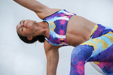 Woman in bold print activewear performing yoga pose in natural outdoor setting