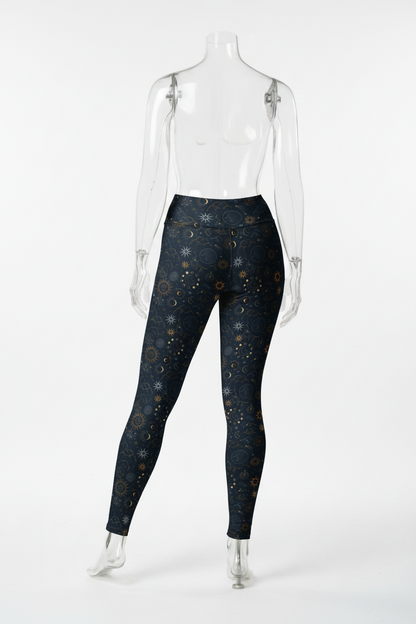 A mannequin modeling high-waisted leggings with a dark navy blue celestial print featuring stars, moons, and suns in gold, white, and light blue, shown against a plain white background.