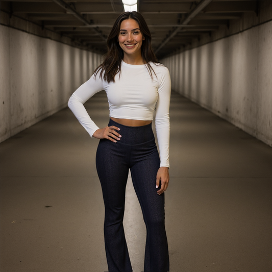 Woman wearing Shadowleaf Flare Leggings with a subtle dark botanical print, high waist, and flared legs, paired with a white long-sleeve crop top, standing in a modern tunnel.