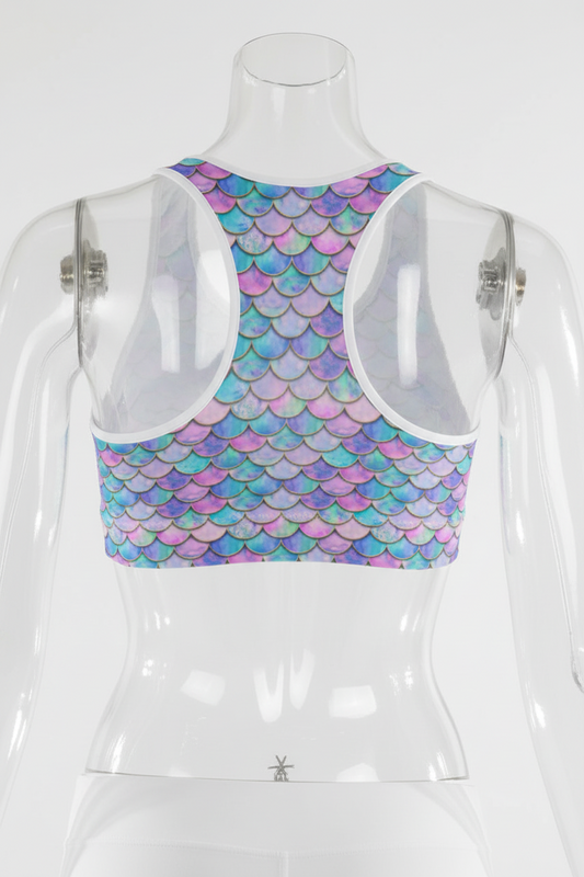 Rear view of a woman wearing a sports bra with a colorful mermaid scale pattern in shades of blue, purple, and pink, paired with white leggings.