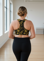 Person wearing a black and yellow patterned sports bra and leggings in a room with large windows.