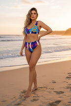 Woman in a colorful bikini standing on a beach with sunset in the background