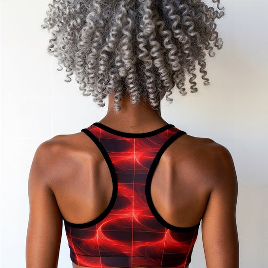 Woman wearing Blaze Ignite Essential Active Bra with a bold red and black abstract grid pattern, shown from the back, against a plain background