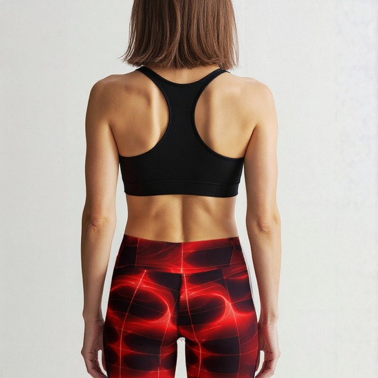 Back view of a woman wearing Blaze Ignite Yoga Shorts with an abstract red and black glowing pattern, paired with a black sports bra, standing against a plain background.