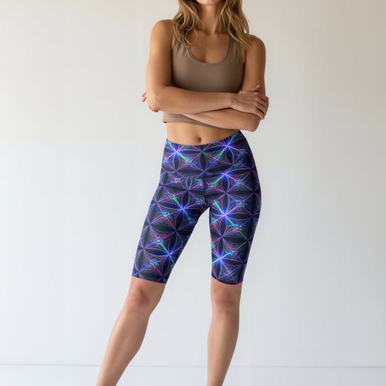Woman wearing a brown tank top and colorful geometric-patterned leggings on a white background