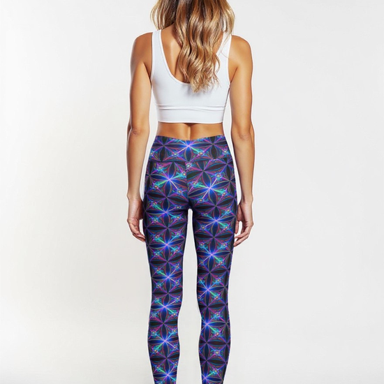 Back view of a woman wearing Blue Voltage Crossover leggings featuring a vibrant blue and purple geometric pattern, with a white sports bra, standing barefoot against a plain white background.