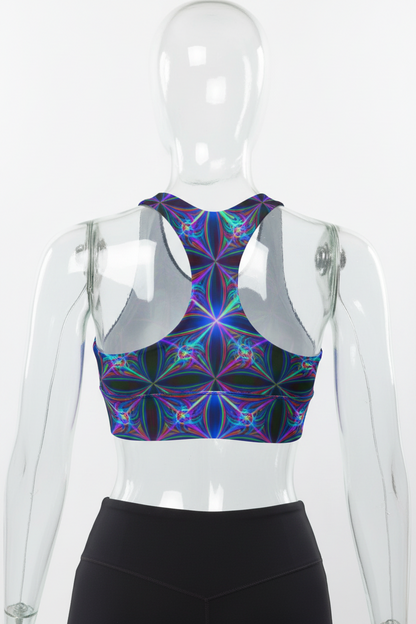 Rear view of a mannequin wearing a sports bra with a vibrant, multicolored kaleidoscopic geometric pattern in purple, blue, green, and pink, paired with black leggings against a white background.