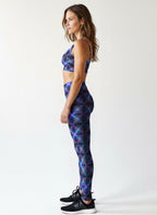 Woman wearing a blue geometric patterned sports bra and leggings set on a white background