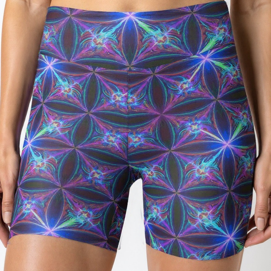 Close-up front view of a woman’s waist and thighs wearing Blue Voltage Yoga shorts, showcasing an electric blue and purple geometric pattern, with a black crop top.