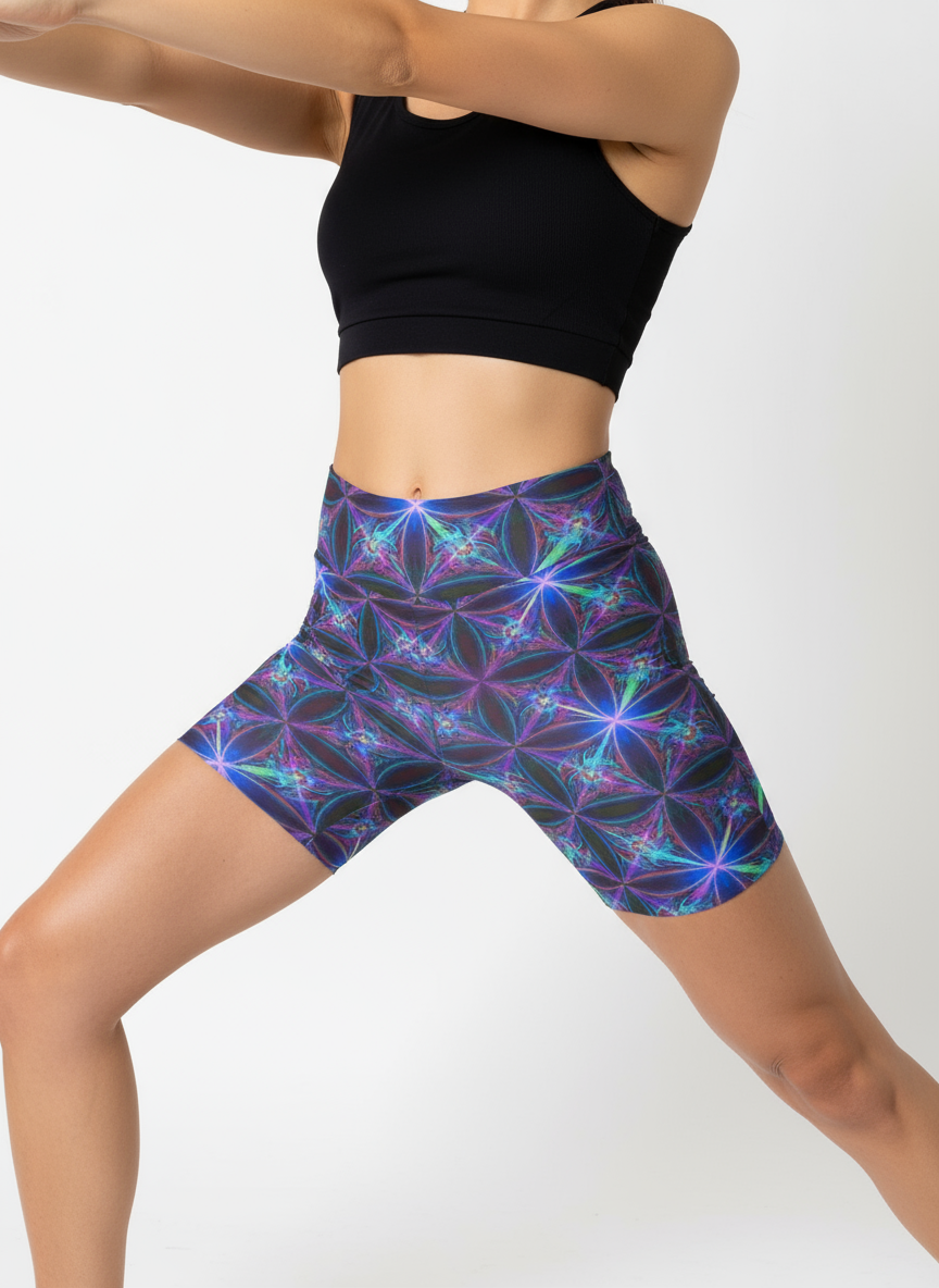 Close-up front view of a woman’s waist and thighs wearing Blue Voltage Yoga shorts, showcasing an electric blue and purple geometric pattern, with a black crop top.