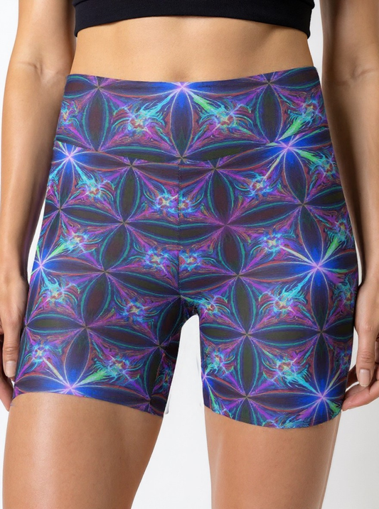Close-up front view of a woman’s waist and thighs wearing Blue Voltage Yoga shorts, showcasing an electric blue and purple geometric pattern, with a black crop top.