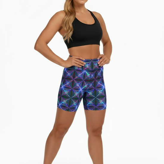Woman wearing a black sports bra and colorful geometric-patterned shorts on a white background