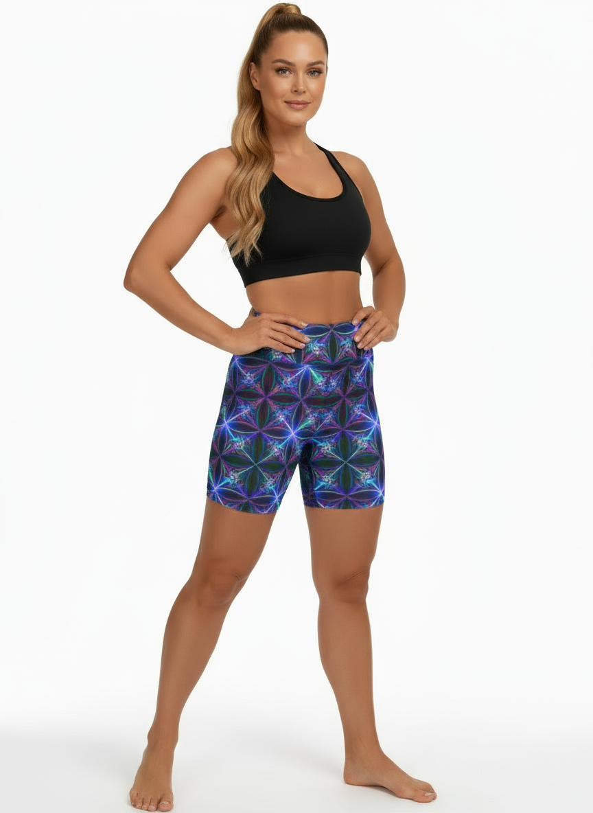 Woman wearing a black sports bra and colorful geometric-patterned shorts on a white background