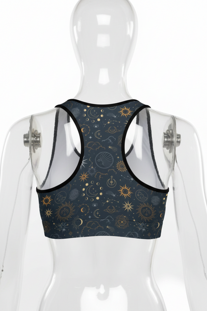 Back view of a mannequin wearing a racerback sports bra with a dark navy blue celestial print featuring gold suns, moons, and stars, set against a plain white background.