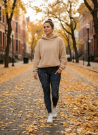 Woman walking on a leaf-covered street in an urban setting
