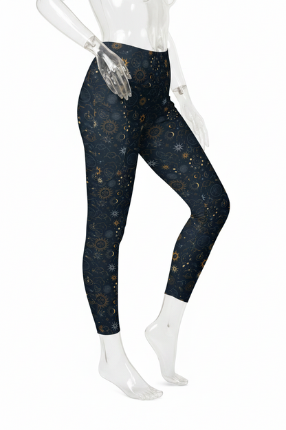 A mannequin modeling high-waisted leggings with a dark navy blue celestial print featuring stars, moons, and suns in gold, white, and gray, paired with white sneakers against a plain white background.