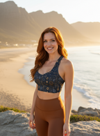 Woman in athletic wear standing on a beach with mountains in the background
