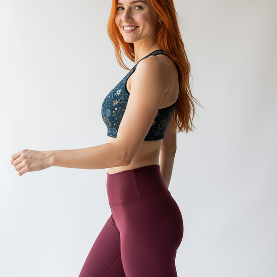Woman wearing a sports bra and leggings on a plain background