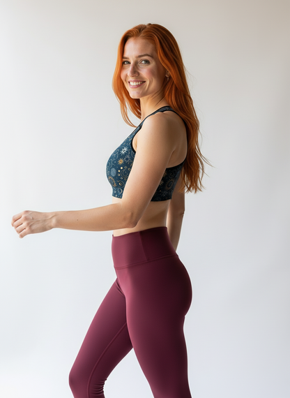 Woman wearing a sports bra and leggings on a plain background