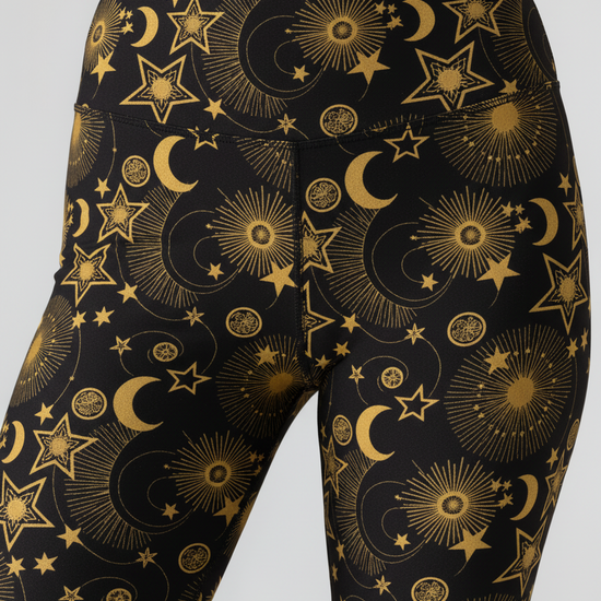 Black leggings with gold celestial pattern on a gray background