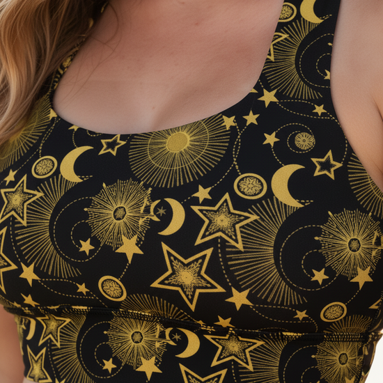 Black sports bra with gold celestial pattern worn by a person