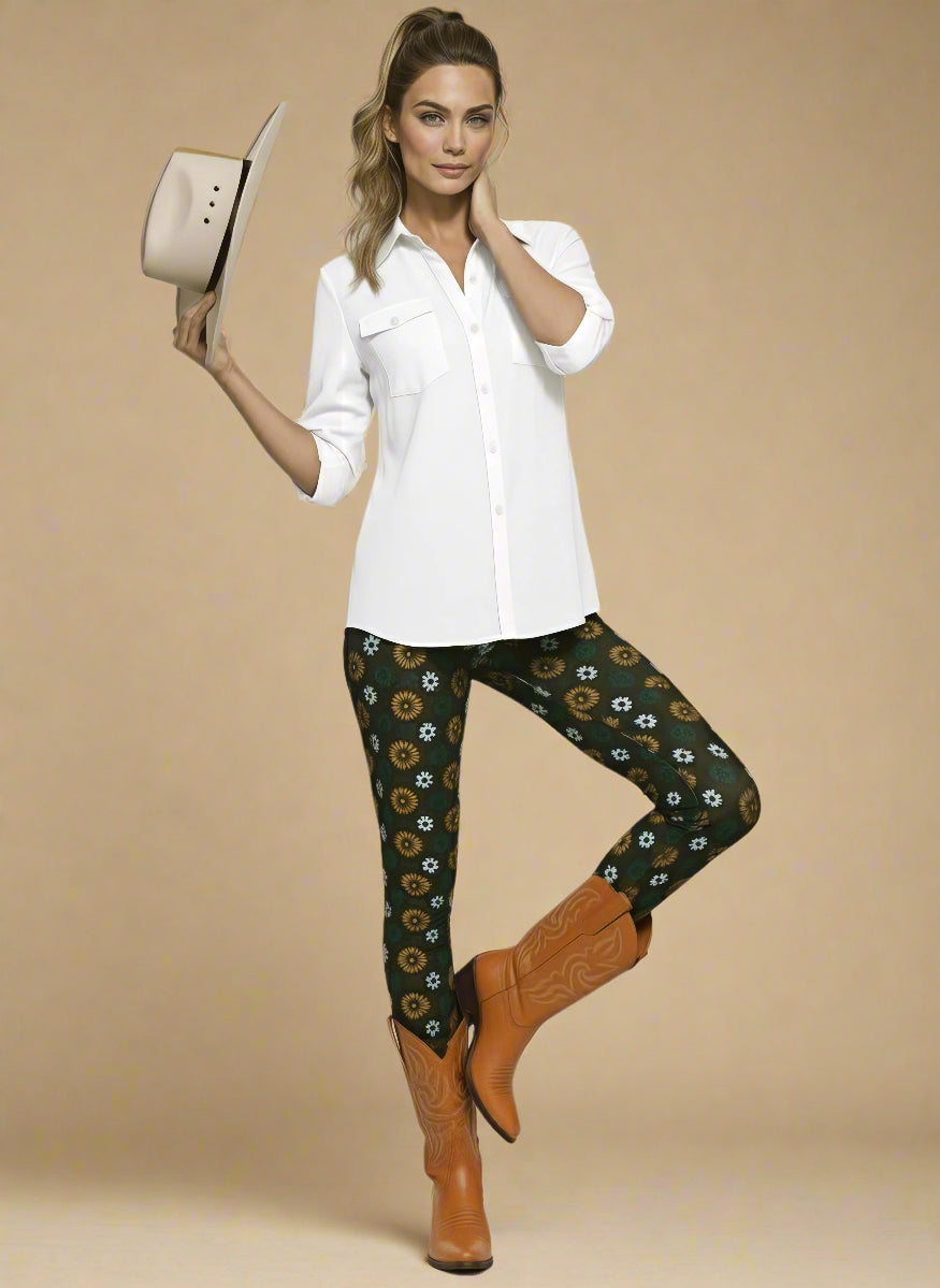 Model wearing Country Diamond Leggings with white and yellow floral print on dark green base, styled with cognac tan cowboy boots and crisp white button-up blouse; outfit blends Western charm with modern activewear