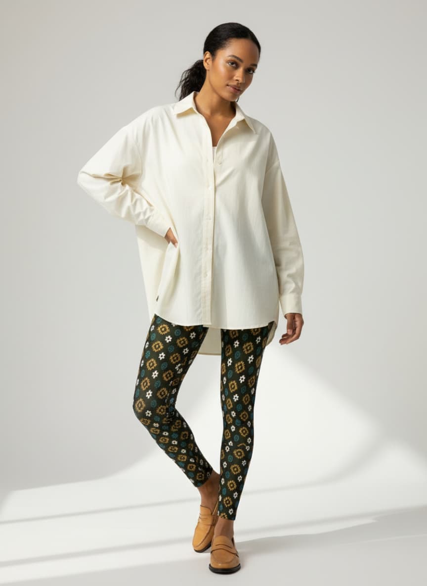 Woman wearing a white shirt and patterned pants on a plain background