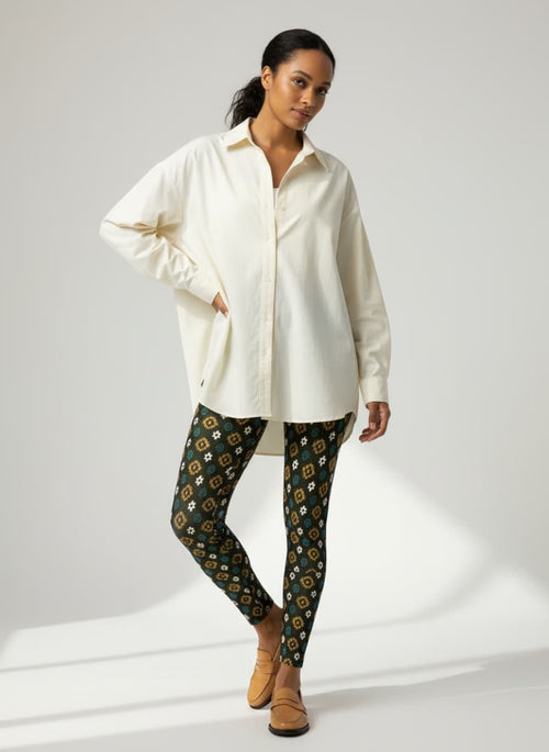 Woman wearing a white shirt and patterned pants on a plain background