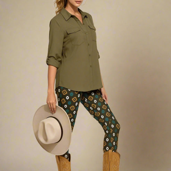 Model wearing Country Diamond Yoga Leggings with dark green base and white and yellow floral print, styled with mustard ochre cowboy boots and an olive green button-up blouse; outfit blends earthy tones with Western-inspired fashion and modern activewear.