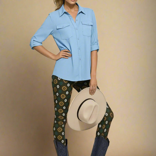 Model wearing Country Diamond Yoga Leggings with dark green base and white and yellow floral print, styled with deep navy cowboy boots and a light sky-blue button-up blouse; outfit blends modern activewear with Western-inspired fashion