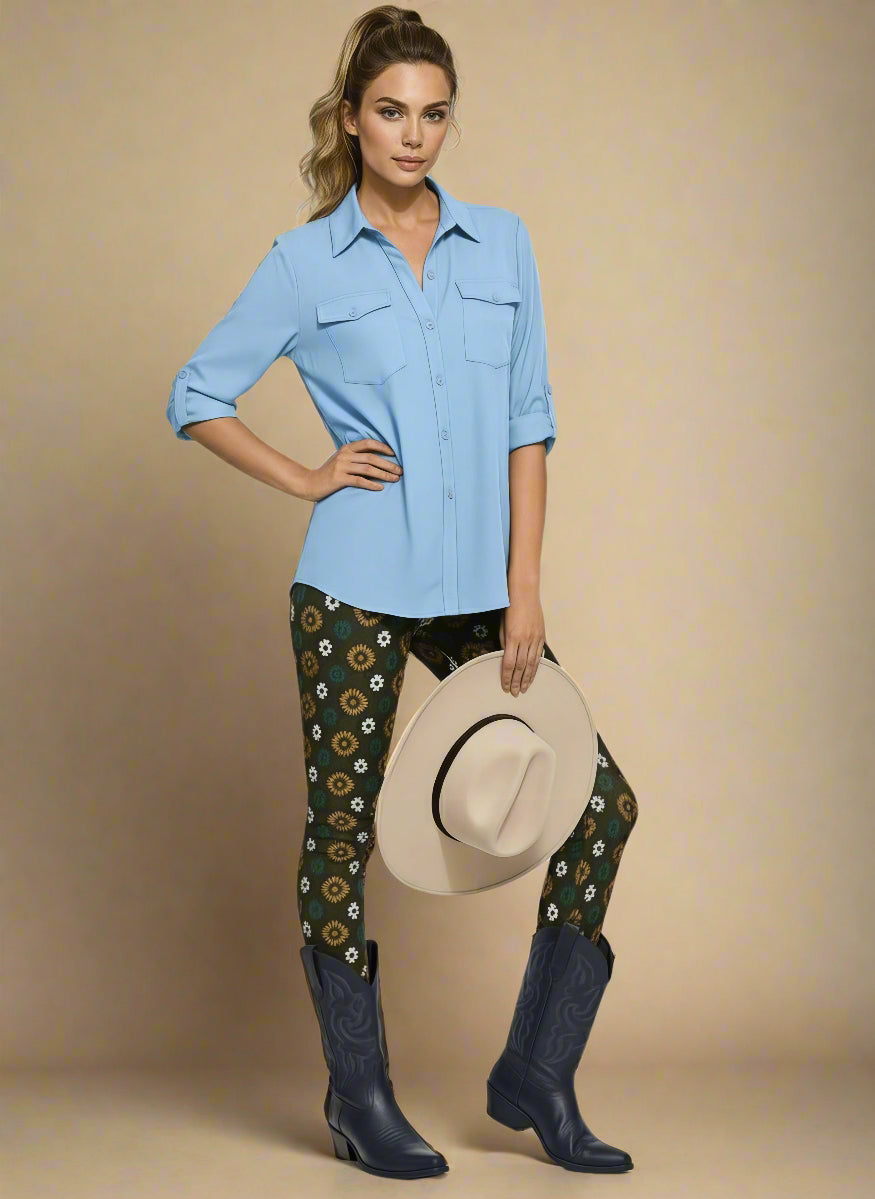 Model wearing Country Diamond Yoga Leggings with dark green base and white and yellow floral print, styled with deep navy cowboy boots and a light sky-blue button-up blouse; outfit blends modern activewear with Western-inspired fashion