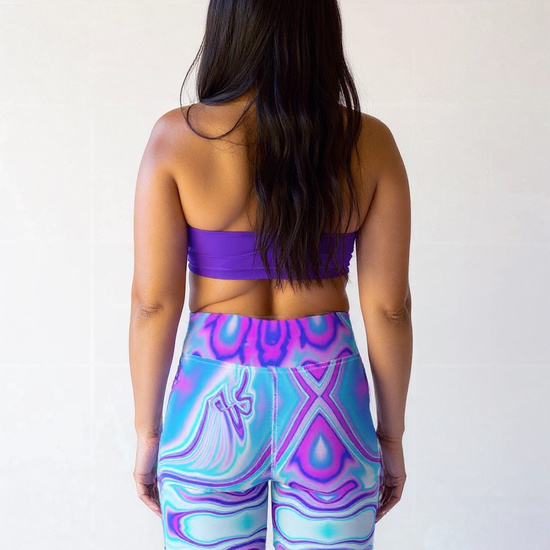 Plus-size woman shown from the back wearing Dreamwave Yoga Shorts with a vibrant blue, purple, and pink swirl pattern, paired with a purple sports bra.