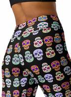 Colorful sugar skull pattern on black leggings worn by a person.