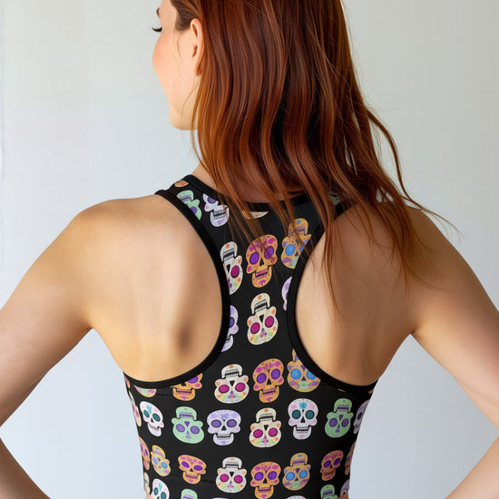 Woman wearing a black tank top with colorful skull pattern against a plain background