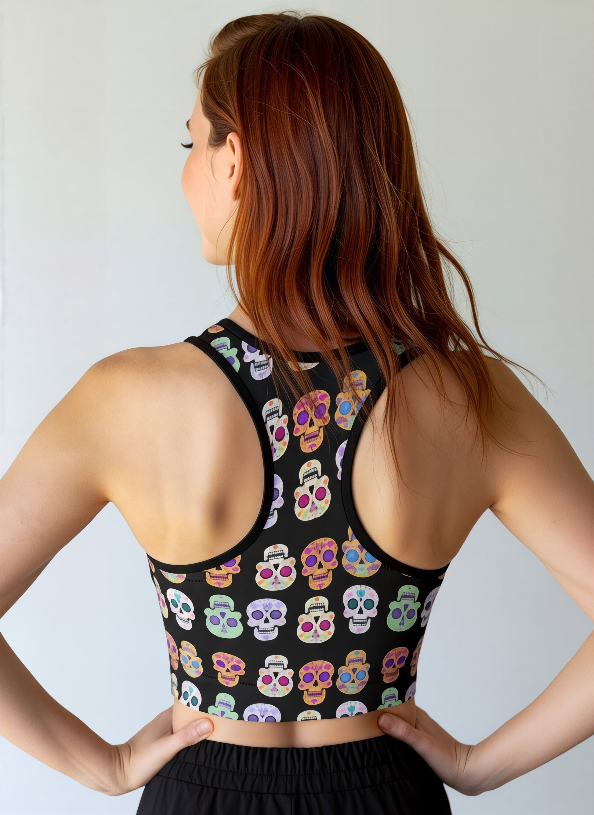 Woman wearing a black tank top with colorful skull pattern against a plain background