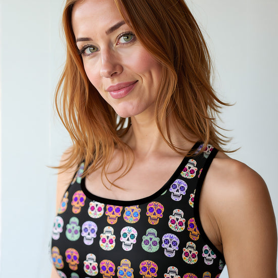Woman wearing Eternal Bloom Essential Active Bra with a black base and colourful sugar skull print, smiling and standing against a plain background