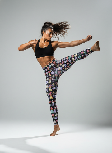 Woman in colorful patterned leggings and black sports bra posing dynamically on a gray background