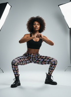 Woman in black sports bra and colorful leggings posing in a studio setting with lighting equipment.