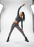 Person wearing a gray long-sleeve top and colorful patterned leggings posing in a studio setting.