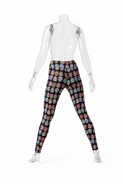 A person modeling high-waisted leggings with a black background and an all-over colorful sugar skull print, shown from the waist down against a plain white studio background.