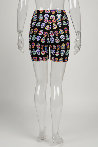 A mannequin modeling black biker shorts with a colorful sugar skull pattern, shown from the back against a plain white background.