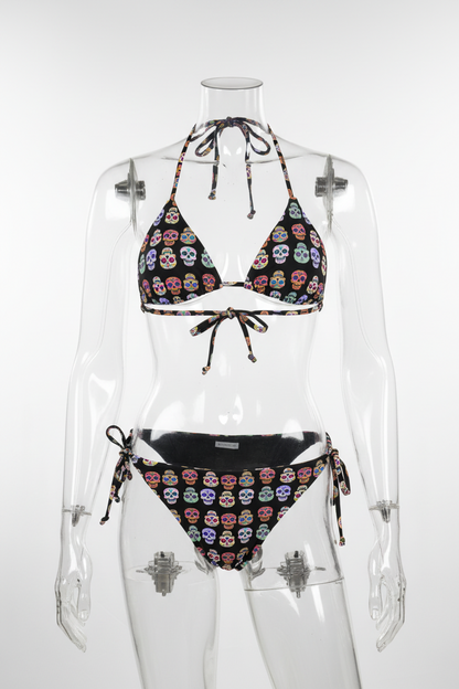 A two-piece  string bikini set featuring a black base printed with colorful sugar skull motifs, shown against a plain white background.