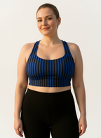 Woman wearing a blue and black striped sports bra and black leggings on a light gray background