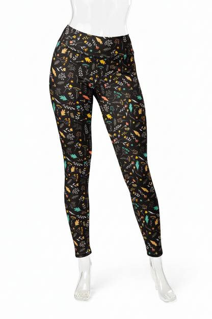 A mannequin modeling black leggings with a colorful all-over abstract pattern on a plain white studio background.