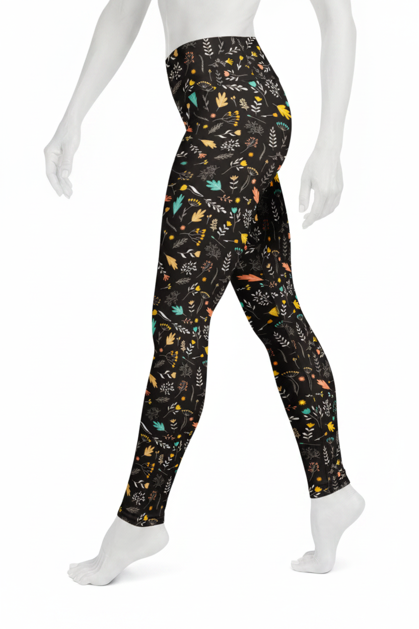 A mannequin wearing high-waisted leggings with a black background and a colorful, playful pattern of birds, leaves, and abstract shapes in yellow, teal, orange, and white.