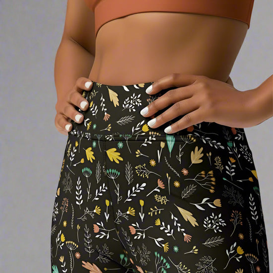 Front, close view of person wearing a brown sports bra and black floral pants on a gray background